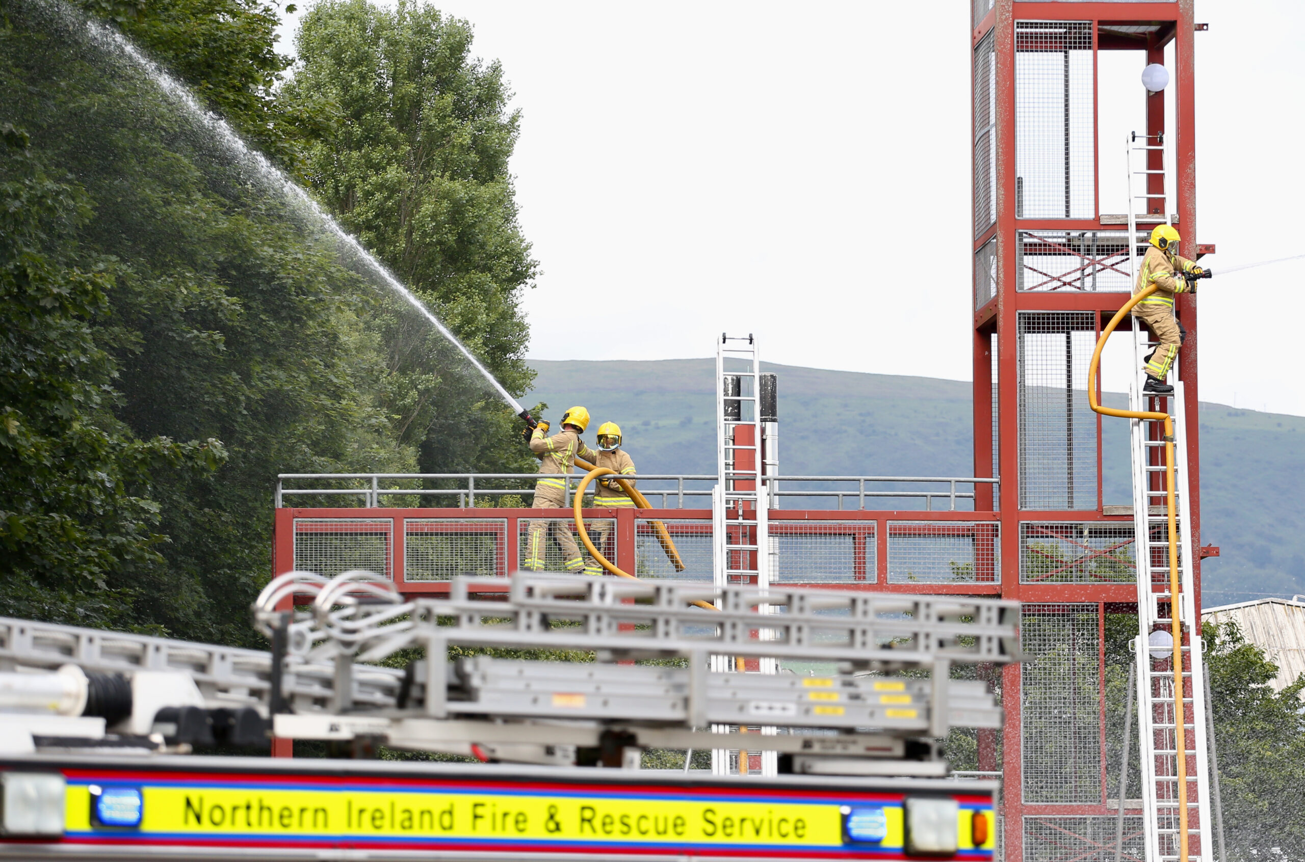 Firefighters using hose and ladders.