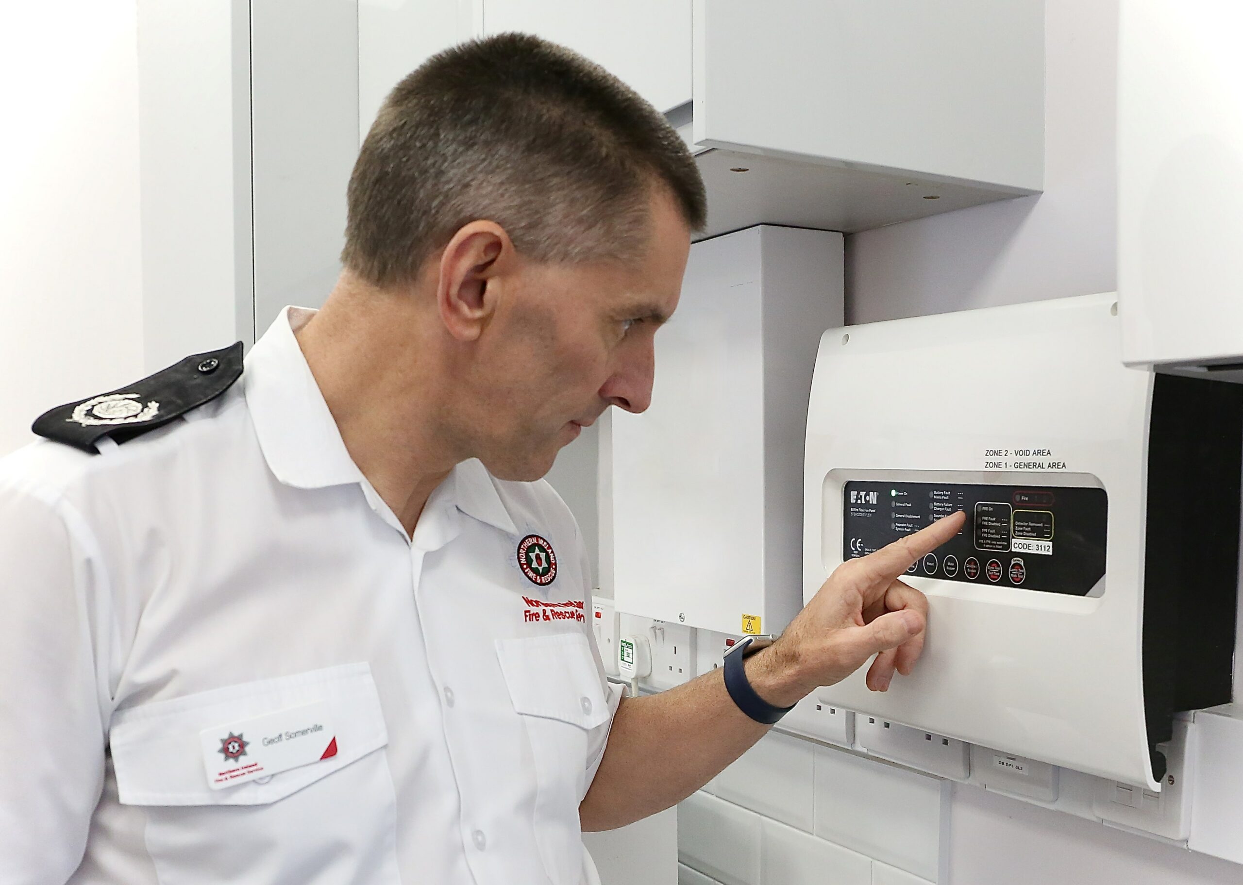 Northern Ireland Fire & Rescue Service Group Commander Geoff Somerville inspects an automatic fire alarm system